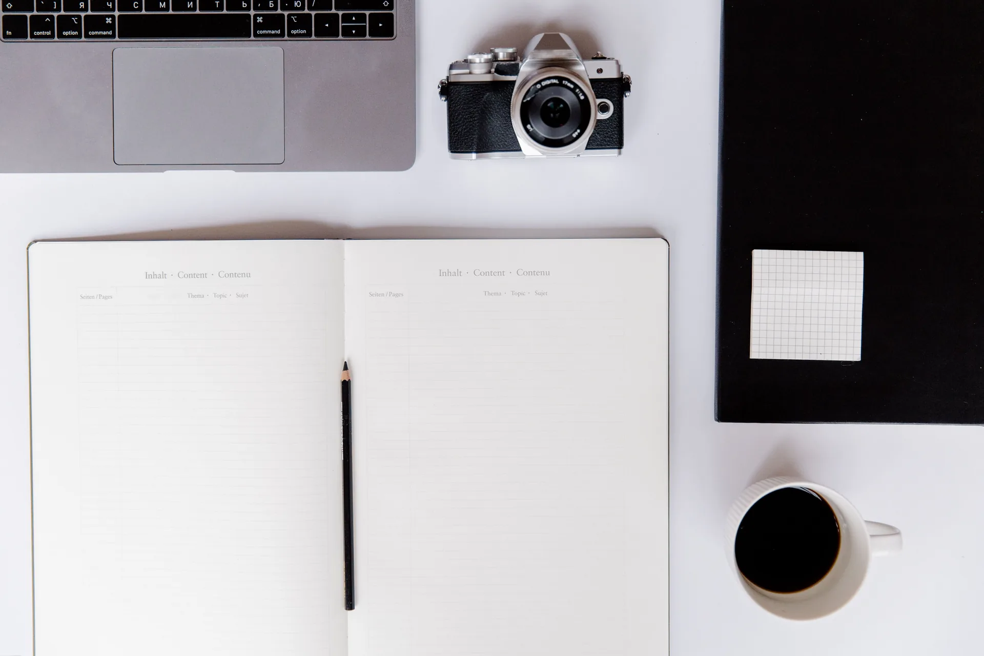 Creative desk with a camera, open notebook and coffee