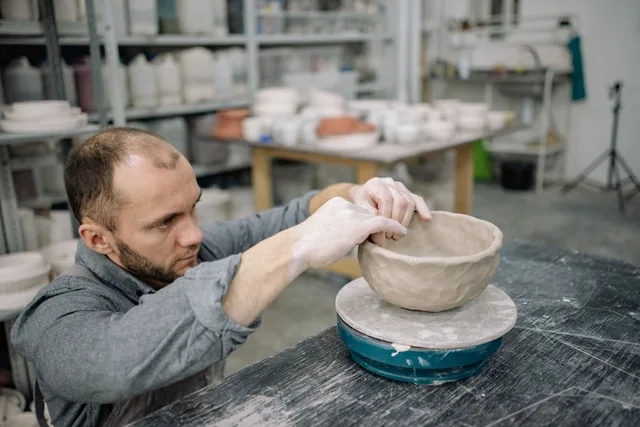 A ceramic artist shaping clay in a workshop